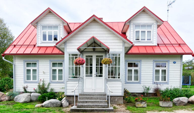 Blog 3 A white house with a bright red metal roof featuring dormer windows and a small covered porch.