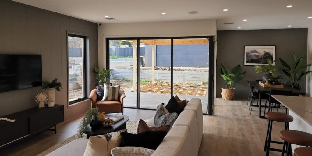 A freshly painted modern living room in Bendigo featuring neutral wall colours, large windows, indoor plants, and stylish furniture after professional interior painting services.