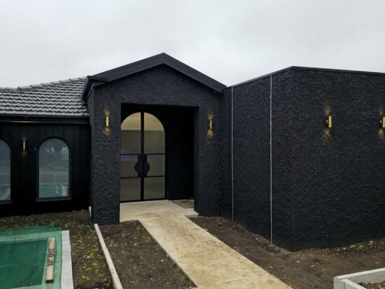 Blog 1 Black textured house exterior with an arched doorway and windows.