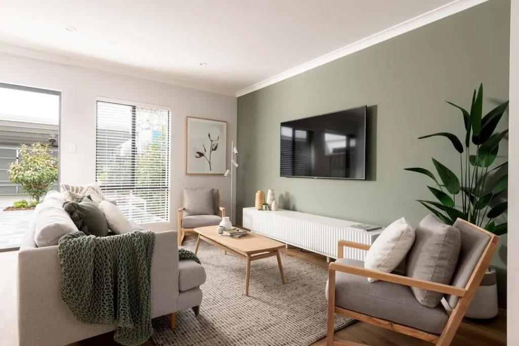 A modern living room painted in a warm greige with a plush cream sofa and natural wood coffee table, showcasing a interior paint colour trend