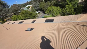 A wide tan corrugated roof with a rooftop vent and visible sun damage before undergoing roof painting and repair services in Bendigo.