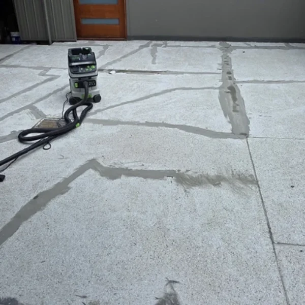 A close view of concrete floor repairs with visible patched sections and equipment used for preparation before epoxy coating services in Bendigo.