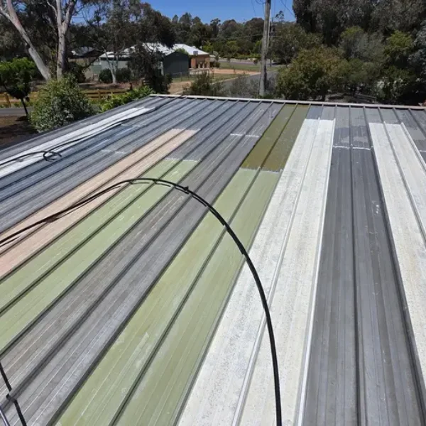 A weathered metal roof with faded multi-coloured panels showing signs of deterioration before receiving professional roof painting and repair services in Bendigo.